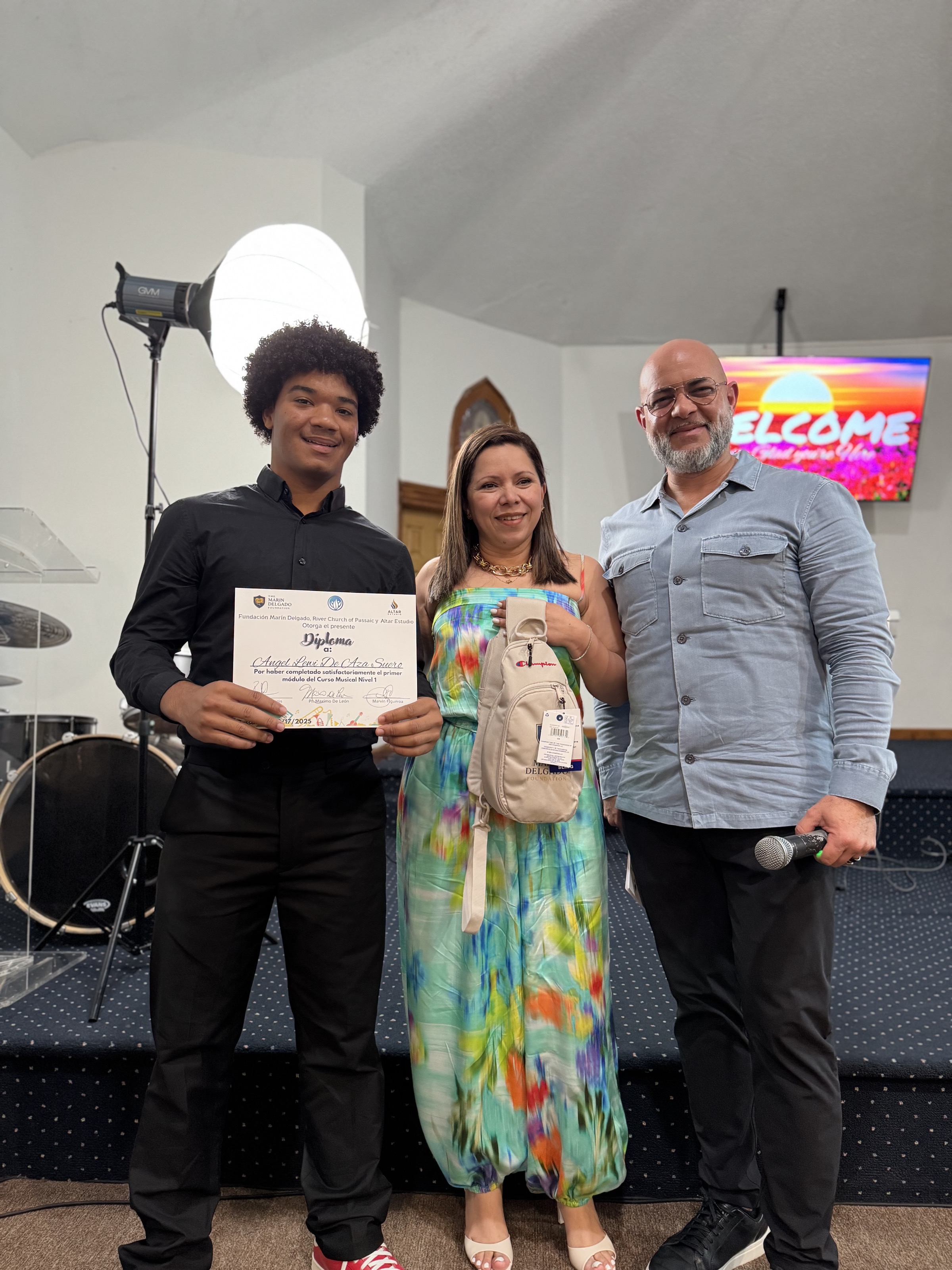 A student holds his diploma after completing the Foundation’s music program, flanked by mentors from the Foundation.
